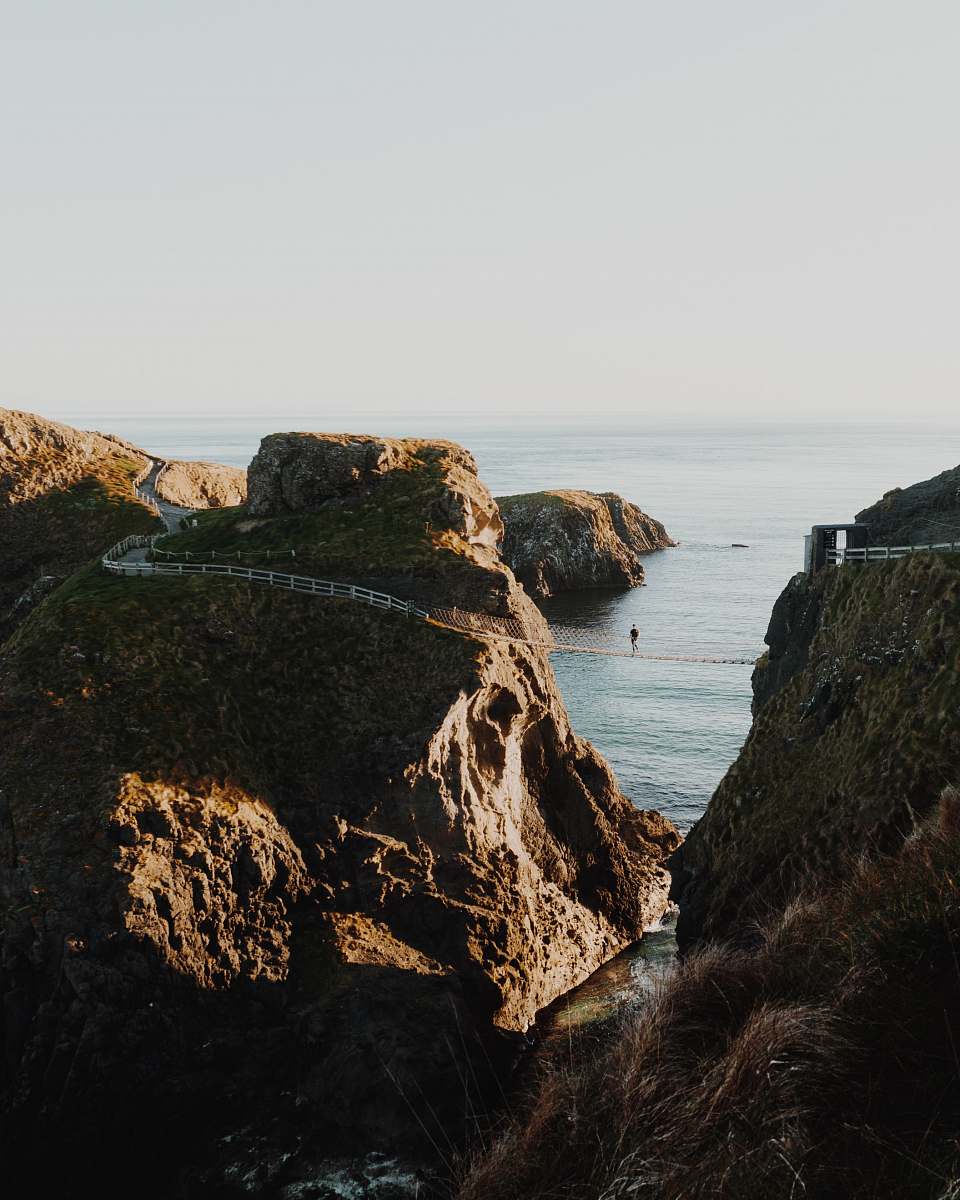 cliff person on hanging bridge during daytime outdoors